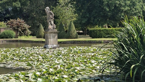 A statue of the god Neptune and lily pads at Westbury Court Garden